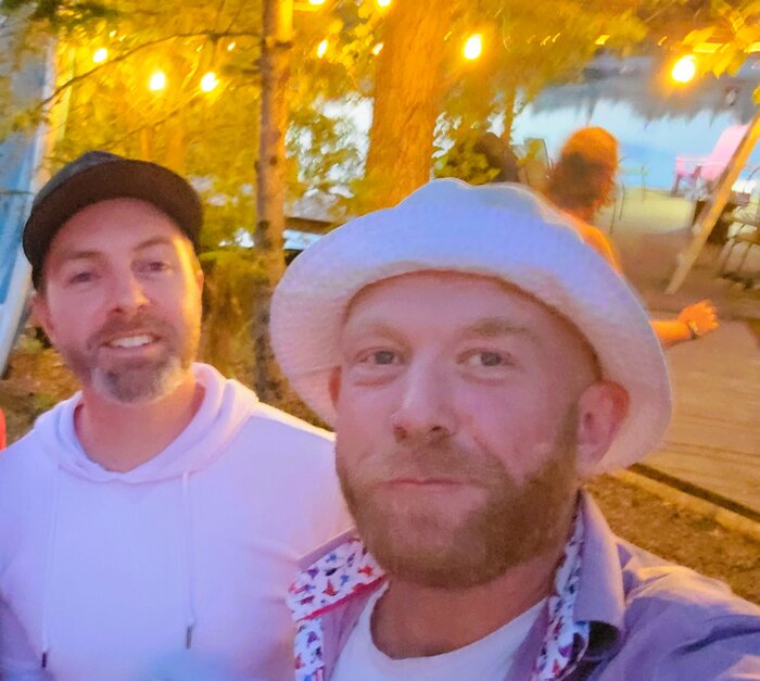 Denis and Greg together on a summer evening, string lights overhead